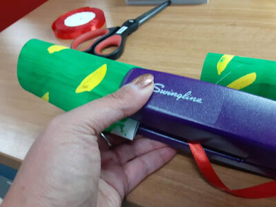 Take one of the toilet paper tubes and staple it to one end of the ribbon (this is the tail end of your snake).