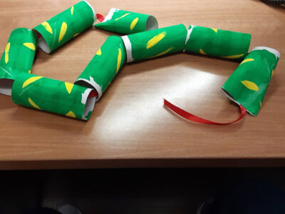 Leaving the extra ribbon at visible, staple the last toilet paper tube to the ribbon