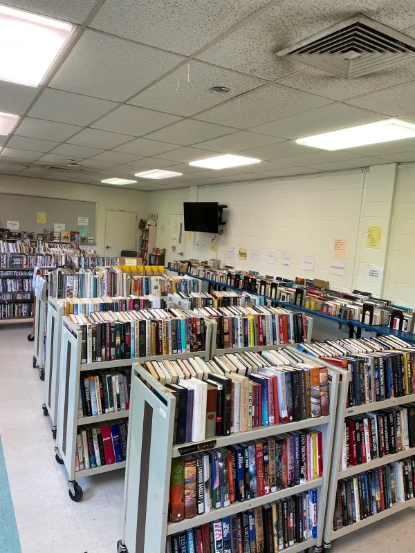 Room filled with organized books on rolling carts, bright overhead lighting, and a wall-mounted TV. It gives a calm, studious atmosphere.